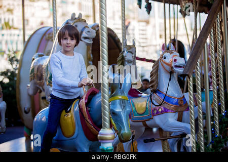 Sweet boys, brothers, riding in a Santa Claus sledge on a merry-go-round, carousel attraction in Europe, active children, wintertime