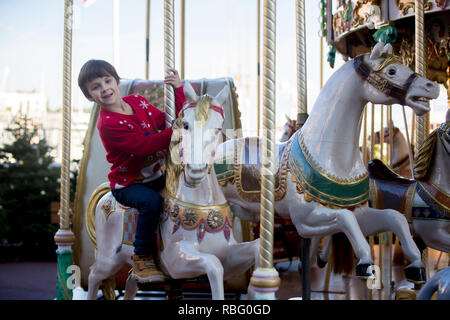 Sweet boys, brothers, riding in a Santa Claus sledge on a merry-go-round, carousel attraction in Europe, active children, wintertime