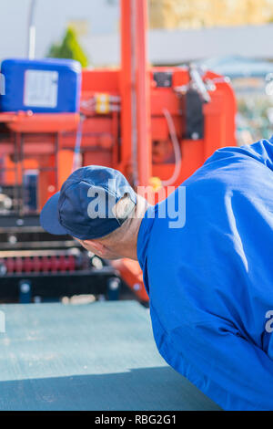 Worker pressing buttons on CNC machine control board in factory. vertical photo Stock Photo