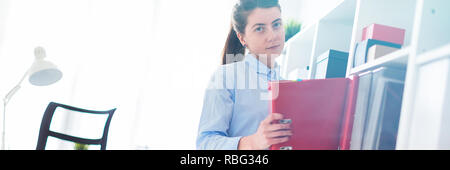 A young girl in the office takes out a folder with documents from the shelter. Stock Photo