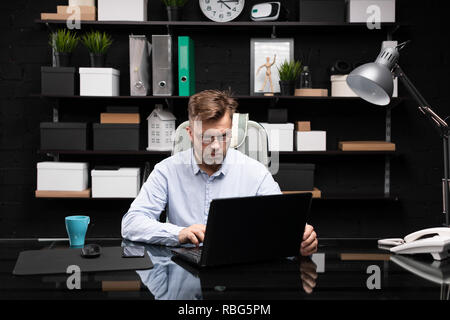 Serious businessman working on laptop and drinking coffee Stock Photo