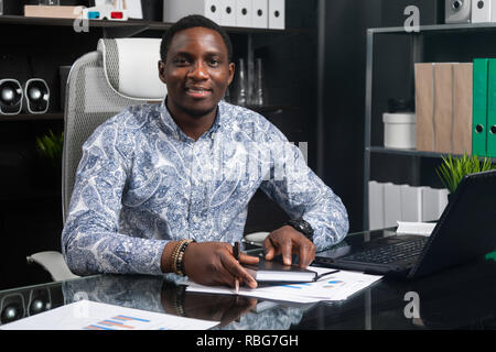 Portrait of Beautiful young African American businessman working with documents and laptop in office Stock Photo