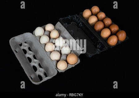 Twenty chicken eggs in carton and plastic boxes, isolated on black felt background. Stock Photo