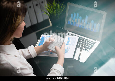 Businesswoman investment consultant analyzing company annual financial report balance sheet statement working with calculator and laptop Stock Photo