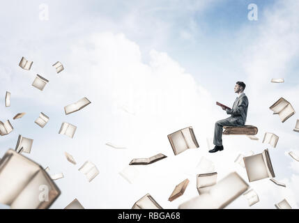 Man reading book and many of them flying in air Stock Photo