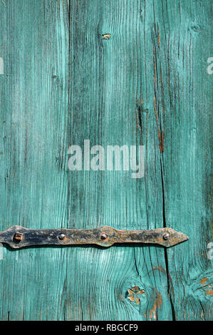 Part of an old weathered green wooden door with rusty metal fittings Stock Photo