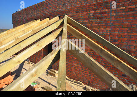 Roofing Construction. Close up on wooden rafters, eaves, wooden beams installed on brick wall with bitumen waterproofing membrane and metal anchors at Stock Photo