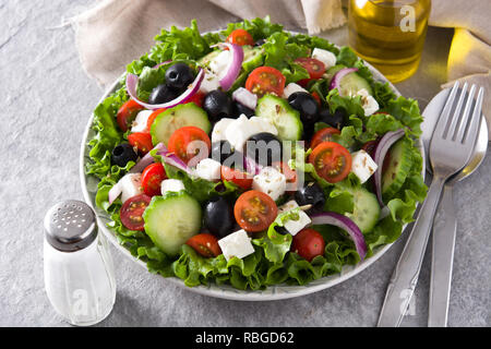 Fresh Greek salad in Plate with black olive,tomato,feta cheese, cucumber and onion on gray background. Stock Photo