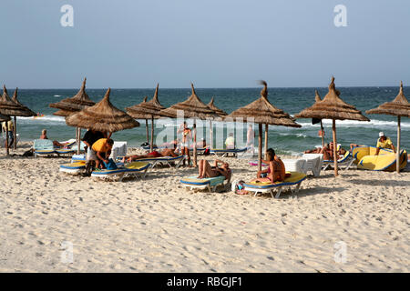 Tourists laingh under the parasols on the beach of Sousse Stock Photo