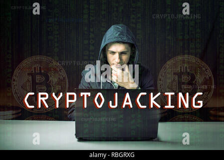 A hacker with a face is trying to steal cryptocurrency using a computer. Fraud and scam at Cryptojacking Stock Photo