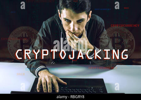A hacker with a face is trying to steal cryptocurrency using a computer. Fraud and scam at Cryptojacking Stock Photo