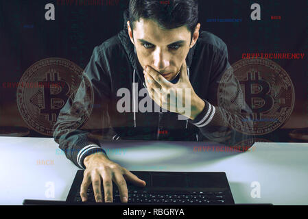 A hacker with a face is trying to steal cryptocurrency using a computer. Fraud and scam at Cryptojacking Stock Photo