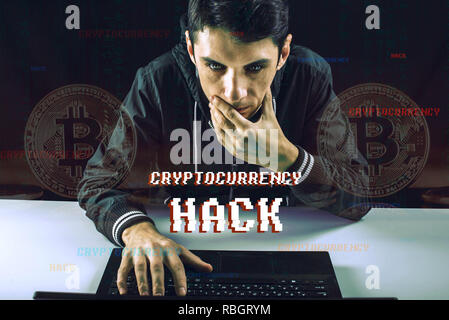 A hacker with a face is trying to steal cryptocurrency using a computer. Scam at Cryptojacking Stock Photo