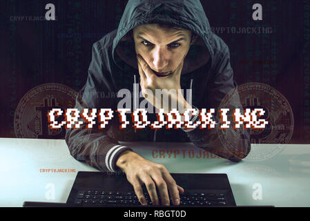 A hacker with a face is trying to steal cryptocurrency using a computer. Scam at Cryptojacking Stock Photo
