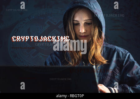 A girl hacker with a face is trying to steal cryptocurrency using a computer. Fraud and scam at Cryptojacking Stock Photo