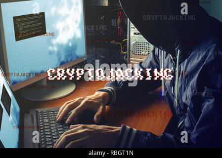 An anonymous hacker without a face is trying to steal cryptocurrency using a computer. Fraud and deception at Cryptojacking Stock Photo