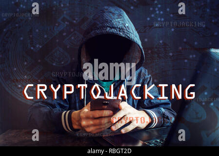 An anonymous hacker without a face is trying to steal cryptocurrency using a computer. Fraud and deception at Cryptojacking Stock Photo