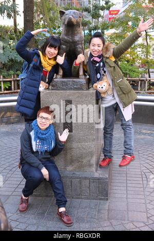 TOKYO, JAPAN - DECEMBER 3, 2016: People visit Hachiko dog statue in Shibuya, Tokyo. Hachiko was a famous dog who waited for owner after his death. Stock Photo