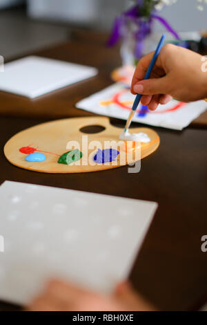 Close up colored palette with paints and brush in hand. Stock Photo