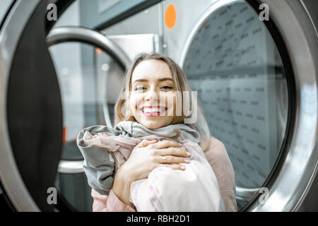 Portrait of a cheerful woman with clean and dried clothes in the laundry Stock Photo