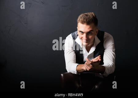 Portrait of young handsome man wearing white shirt standing on the gray background and looks slyly Stock Photo