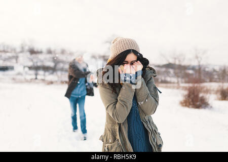 Snowball fight. Winter couple having fun playing in snow outdoors. Young joyful happy young man and woman. Stock Photo