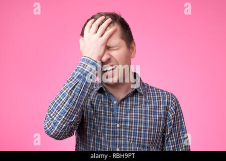 Caucasian man showing how much his head hurts, experiencing pain, looking miserable and exhausted. Headache or migraine concept Stock Photo