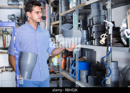 concentrated male is choosing plastic trumpet in the plumbing department in building store Stock Photo