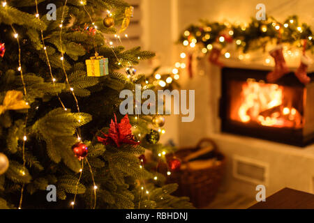 Christmas tree and home holiday decor near the modern marble fireplace in the room. Focus on the Christmas tree Stock Photo