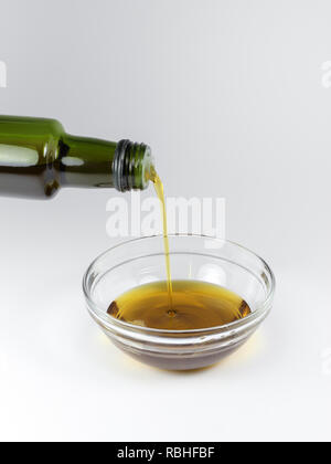 Pouring from a bottle of organic hemp seed oil on a white background Stock Photo