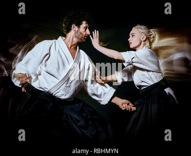 two budokas fighters man and woman practicing Aikido studio shot isolated on black background Stock Photo