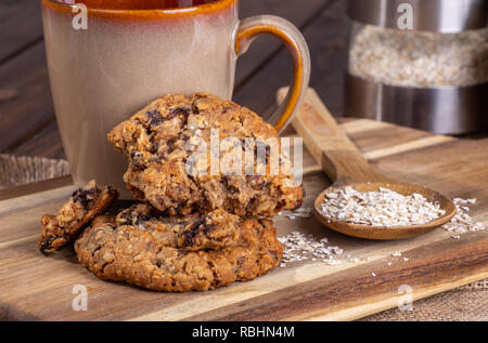 Oatmeal raisin nut cookies and oatmeal flakes on a wooden surface with a coffee cup Stock Photo