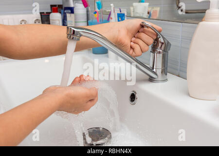 The child opens the faucet in the bathroom, and adjusts the warmth of the water Stock Photo