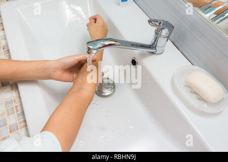 The child washes his hands up to the elbows in the bathroom sink Stock Photo