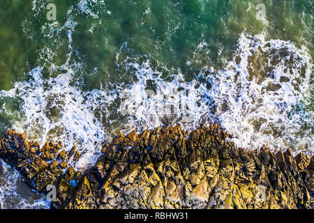 Aerial overhead view of beautiful breaking ocean waves against a rugged rocks Stock Photo