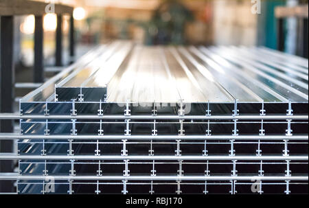 Aluminium profiles placed in a row inside an aluminum profile factory. Stock Photo