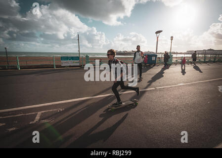 Skateboarders cruise along the promenade on a summers evening in Brighton, East Sussex, UK. Stock Photo