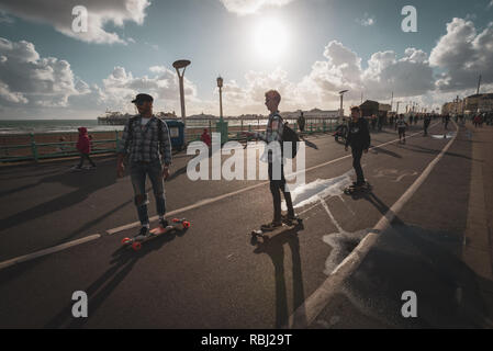 Skateboarders cruise along the promenade on a summers evening in Brighton, East Sussex, UK. Stock Photo