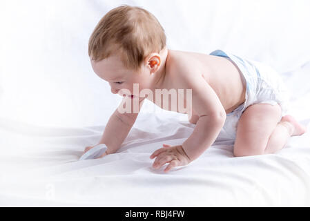 Cute blue-eyed baby 6-9 months smiling and playing on white background. Children's emotions. Cleanliness and care for babies Stock Photo