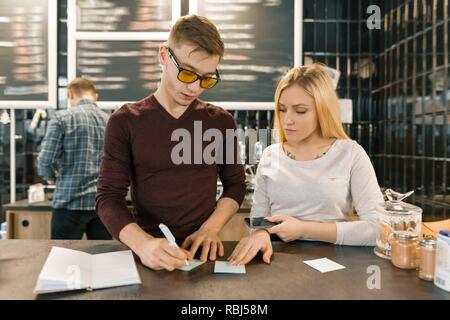 Young people working in coffee shop, man and woman near bar counter, receiving order by phone, barista on the background of coffee machine. Teamwork,  Stock Photo