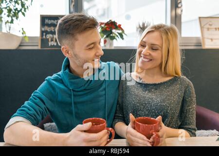Young happy couple in love in cafe, young man and woman together smile hugging drink coffee tea. Stock Photo