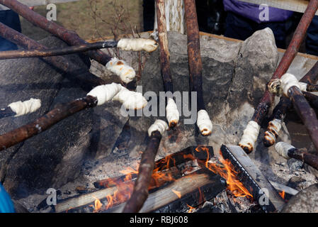 Cooking bannock campfire bread on sticks over an open fire Stock Photo