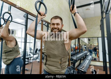 Portrait muscular caucasian bearded man dressed in weighted vest in the gym, military style. Stock Photo