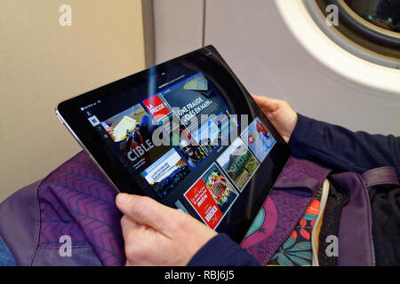 A woman's hands holding a new 12.9 inch iPad Pro and reading her Quebecois newspaper on it. Stock Photo