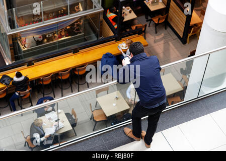 A man using a cellphone in a shopping mall Stock Photo