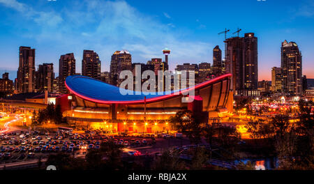 Panorama of Calgary downtown skyline at sunset blue hour showing the iconic Saddledome arena and Calgary Tower in the background with surrounding city Stock Photo
