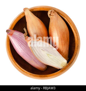 Long shallots, whole and sliced, in wooden bowl. Type of onion, Longor, French variety of Allium cepa. Purple, edible, raw, organic and vegan plant. Stock Photo