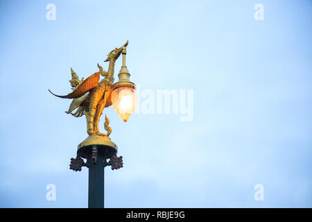 Kanchanaburi, Thailand - December 30, 2018: Golden Swan Sculptural Street Lamp in Thai Contemporary Art glows in twilight on Mon Bridge in Sangkhlabur Stock Photo