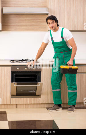 Young contractor repairing oven in kitchen Stock Photo