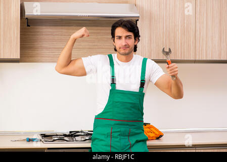 Young contractor repairing oven in kitchen Stock Photo